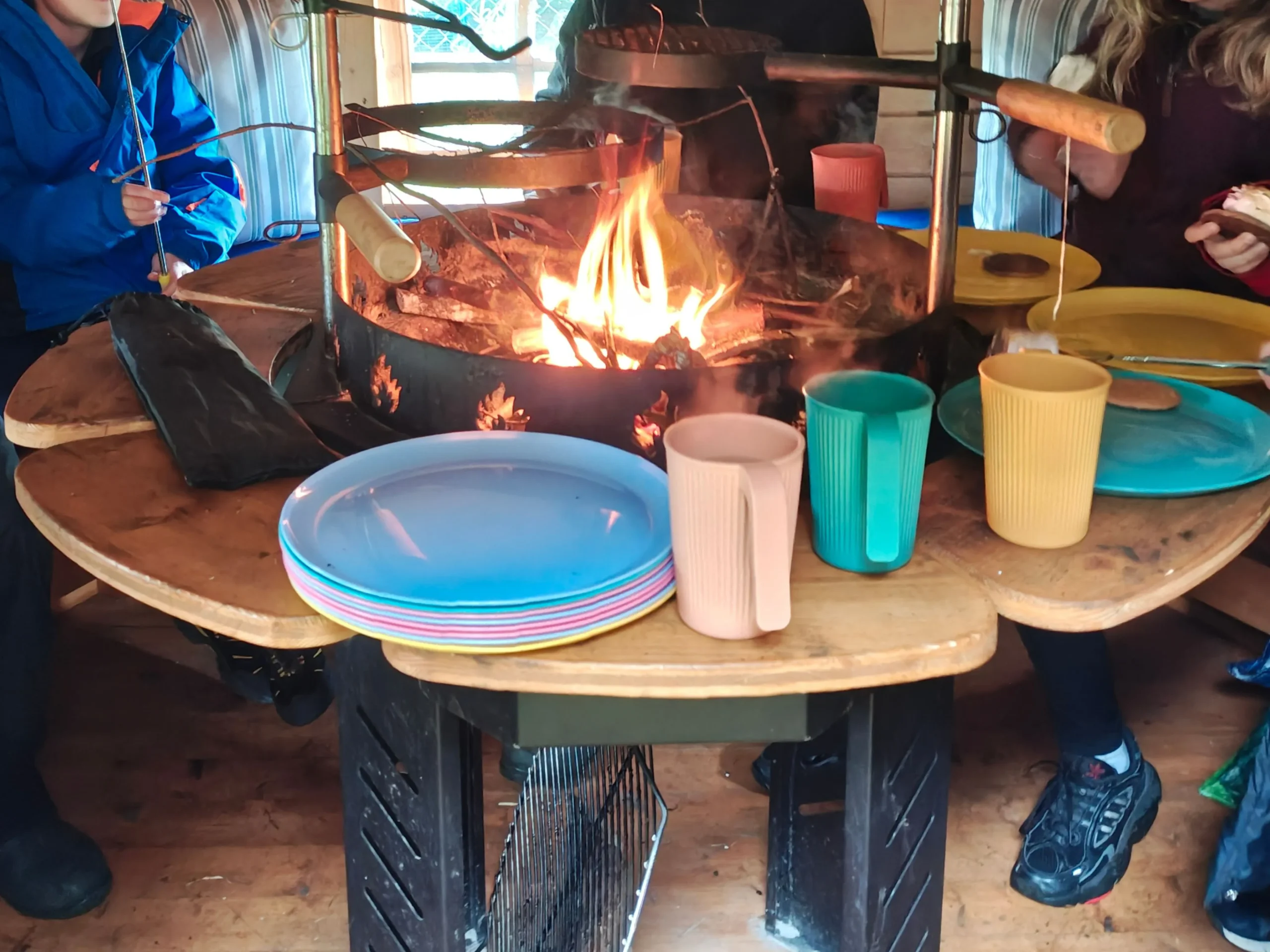 Child at forest school mud kitchen mixing water and soil on tree stump—nature-based play for wellbeing, small-group learning.