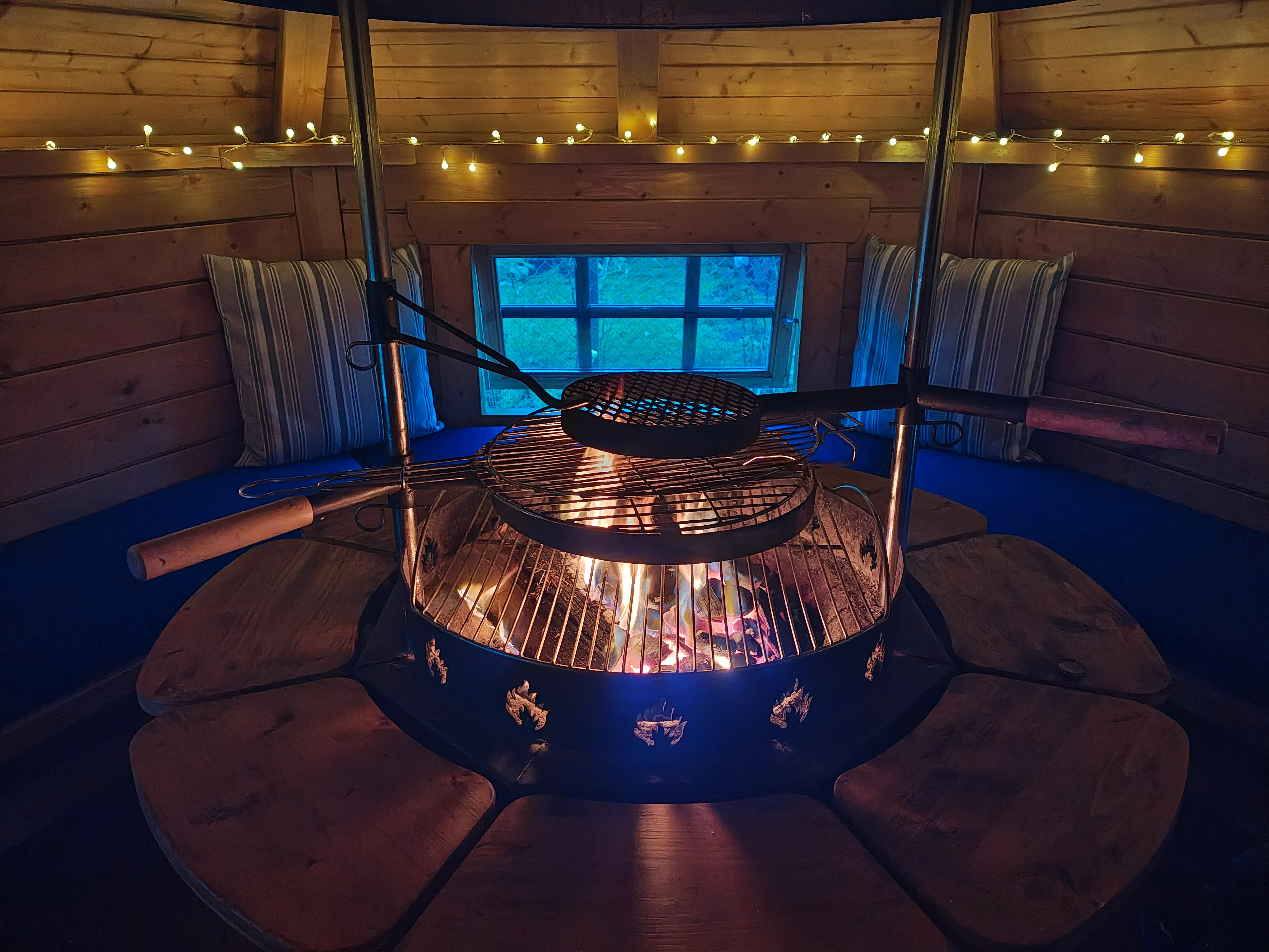 Forest school cabin with fire pit and benches for nature-based therapeutic play, wellbeing workshops and small group learning.